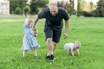 Wall Mural - happy father's day, dad playing and having fun with kids outdoors on a lawn field