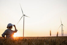 Farmer Looking At Wind Turbines Standing In Wheat Field