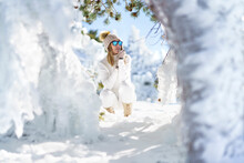Contemplative Woman Wearing Sunglasses Crouching On Snow