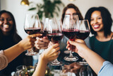 Fototapeta Londyn - Group of friends toasting with red wine glasses, celebrating Christmas holidays together at a festive lunch party