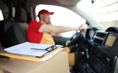 courier in uniform in car and receipt documents on clipboard for client. parcel delivery and courier