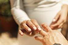 Hand Of Bride Putting Wedding Ring On Groom's Finger