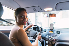 Smiling Young Woman Holding Steering Wheel In Car