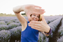 Smiling Woman Showing Finger Frame Sign In Lavender Field