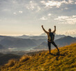 © Westend61 - Hiker standing with arms raised and looking at mountains