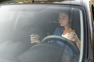 Wall Mural - Woman eating food fast food and drink coffee while driving the car on highway road. Transportation and vehicle