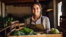 Happy female farmer holding a wooden box with fresh vegetables stands and looks at the camera