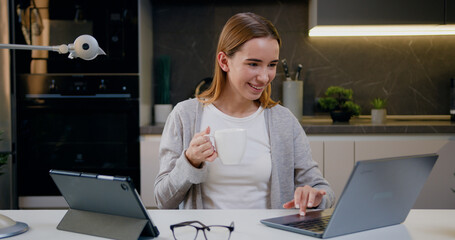 Digital marketing, young caucasian woman with tablet, laptop and home office desk check ux website design or social media seo report. Student girl smiling while checking internet network or reading