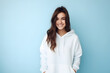 Colorful studio portrait of a beautiful young woman smiling in a white hoodie, pastel blue background. Generative AI