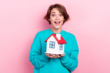 Sticker - Portrait of astonished cute girl wear trendy teal clothes hands hold house rejoice moving new apartment isolated on pink color background