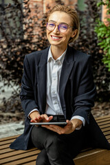 Cute young woman in black suit with a tablet in hands