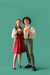 Wall Mural - Young couple in traditional German clothes with beer on green background