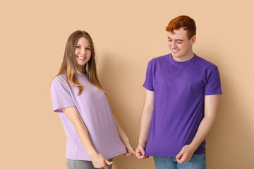 Wall Mural - Young couple in t-shirts on beige background
