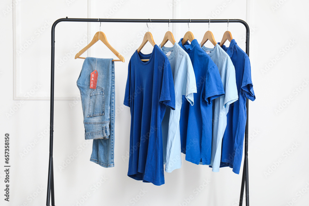 Rack with clothes against light wall. Black Friday sale