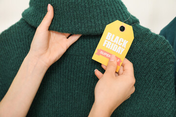 Poster - Female hands with sale tag and sweater, closeup. Black Friday