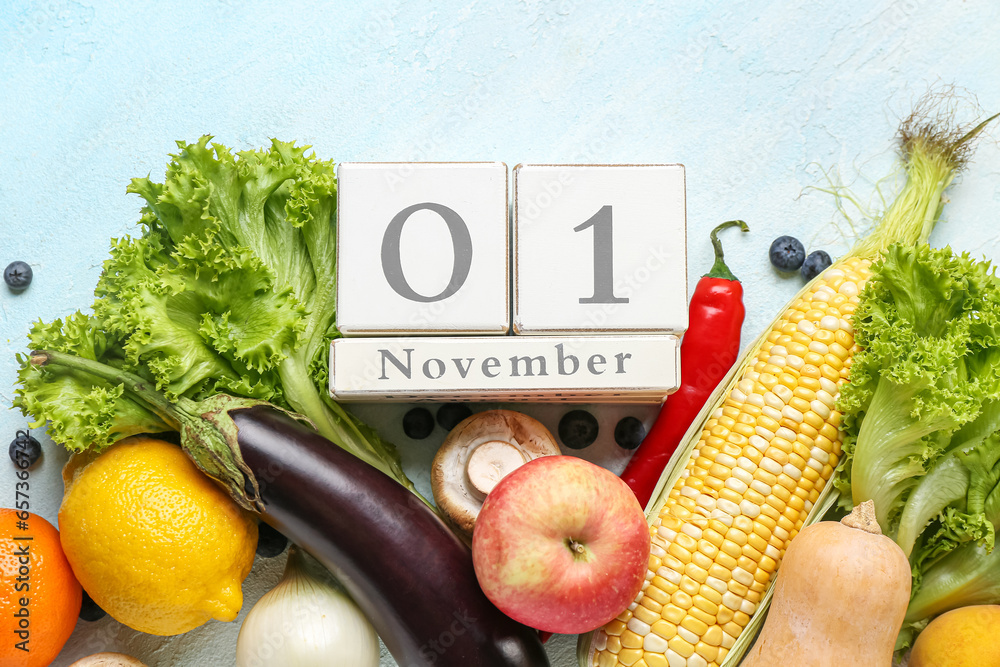 Fresh vegetables, fruits and cube calendar with date NOVEMBER 1 on blue background. World Vegan Day concept