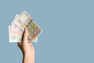 Female hand holding Bulgarian lev banknotes on blue background