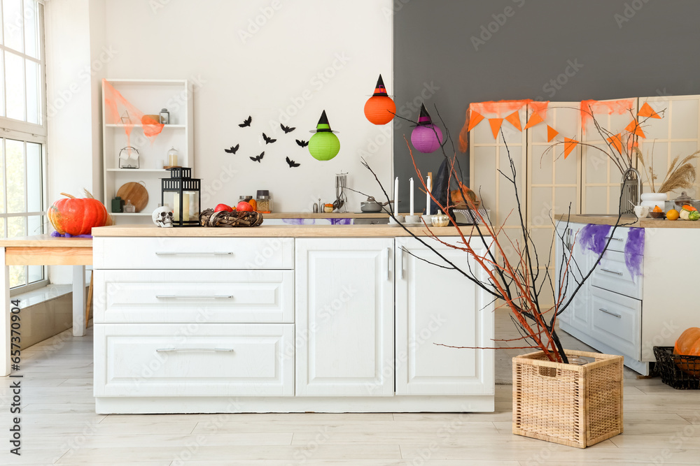 Interior of light kitchen decorated for Halloween with white counters and pumpkins