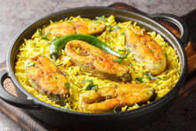 Asian spicy pilaf with fish steaks close-up in a frying pan on the table. horizontal