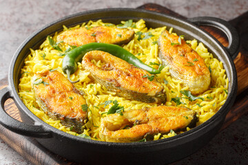 Wall Mural - Asian spicy pilaf with fish steaks close-up in a frying pan on the table. horizontal