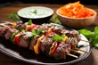 lamb and bell pepper kebabs on skewer with a mint dip in background