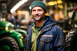 Authentic smiling farmer surrounded by his farming machinery in a garage.