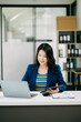 © Nuttapong punna - Young beautiful woman typing on tablet and laptop while sitting at the working white table office
