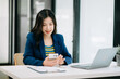 © Nuttapong punna - Young beautiful woman typing on tablet and laptop while sitting at the working white table office