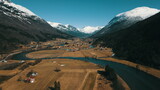 Fototapeta Morze - Aerial view of small village in valley with mountains and river.
