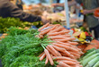 Einkaufen auf dem Wochenmarkt: Blick auf eine Auswahl an knackigen Karotten und anderem Gemüse an einem Verkaufsstand draußen mit Menschen im verschwommenen Hintergrund, selektiver Fokus, Copyspace
