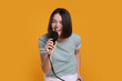 © New Africa - Beautiful young woman with microphone singing on yellow background