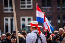 Traditional Dutch Carrier Clothes At Alkmaar Cheese Market With Dutch Flag