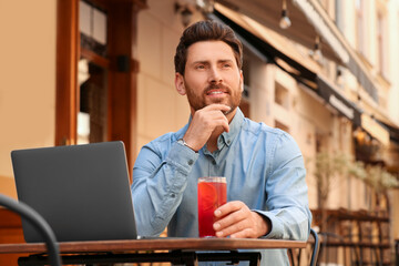 Sticker - Man with drink and laptop at table in outdoor cafe