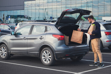 Canvas Print - happy man put groceries bag in car trunk