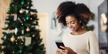 Young African American Woman Ordering Gift During Christmas Holiday At Home Using Smartphone And Credit Card. Shopping Online During Holidays, Internet Banking, Store Online.
