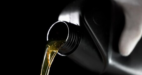 Wall Mural - worker pouring car engine oil from bottle on black background. motor maintenance