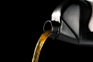 Wall Mural - pouring new motor oil from bottle into car engine. isolated on black background