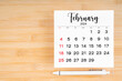 © gamjai - February 2024 calendar page and pen on wooden background.