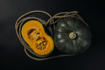 Wall Mural - Green pumpkin on a dark background. Half a pumpkin next to a whole pumpkin