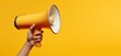 Hand holding megaphone, marketing and sales, yellow background