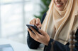 © crizzystudio - Attorney, female lawyer muslim wearing hijab working on business documents, using smartphone to communicate with clients on business contract documents. Justice. Legal service concept in office.