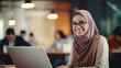 ©  Studio AB Images - Young beautiful woman wearing hijab and glasses sitting at the desk and using her laptop in the office space.
