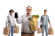 © Ljupco Smokovski - Smiling mature man with a smartphone standing in front of young men with grocery bags