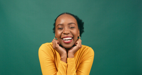 Wall Mural - Beautiful Black woman cups hands under chin in cute pose, green studio