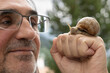 © Guzel - Man holding a big snail on his fist and smiling