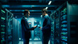© Aram - two young male and female professional engineers stand in a modern data center and work on a computer.