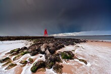 A Red Lighthouse Along The Coast Under A Stormy Sky; South Shields, Tyne And Wear, England