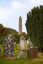 Gravestones In A Cemetery And A Round Tower On A 6Th Century Monastic Site; Glendalough, County Wicklow, Ireland