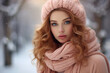 Woman wrapped in a cozy peachy pink scarf against a snowy backdrop