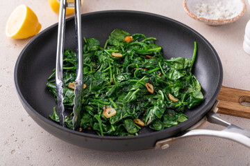 Canvas Print - Sauteed garlic spinach in a pan with slices of crispy garlic